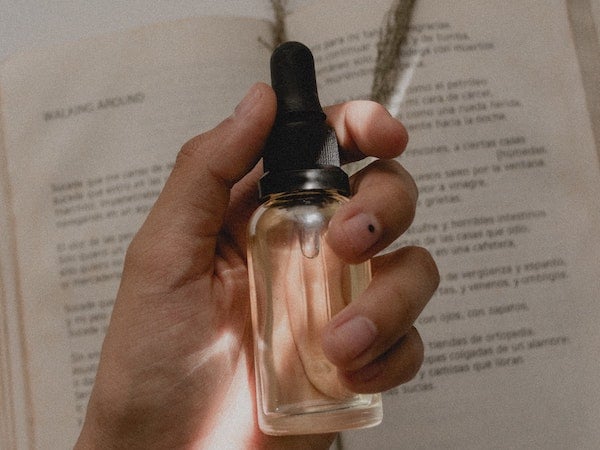A TikTok creator holding a bottle of serum in front of a book, by Angélica Echeverry via Unsplash.