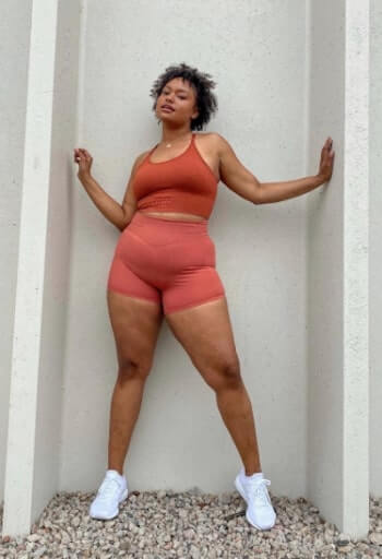 Model wearing a coral Balance Athletica top and biker shorts.