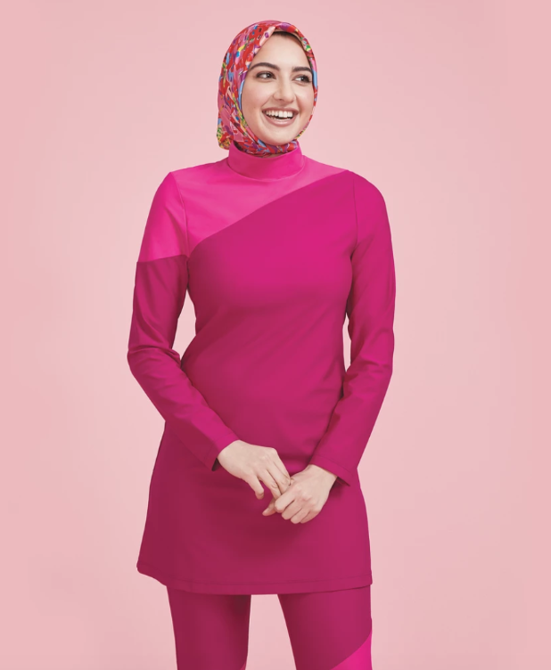 A woman wearing a hijab models Summersalt’s full-coverage swim tunic.