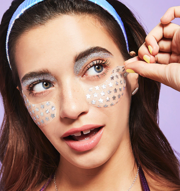 A woman applying Bliss eye masks under her eyes.