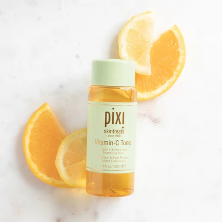 Close up Pixi Beauty’s Vitamin-C Tonic surrounded by orange slices.
