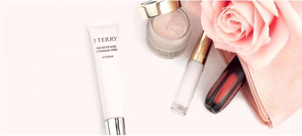 A flat-lay photo featuring ByTerry’s Baume de Rose Lip Scrub and Face Cream.