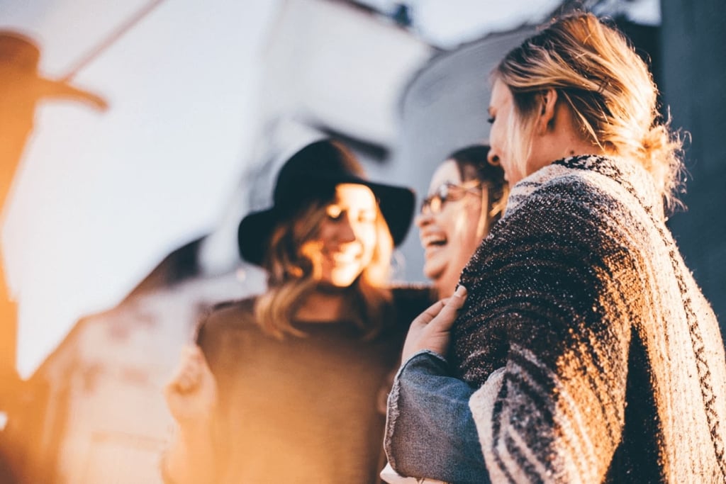 Three women laughing in the sunshine. Priscilla du Preez via Unsplash. 