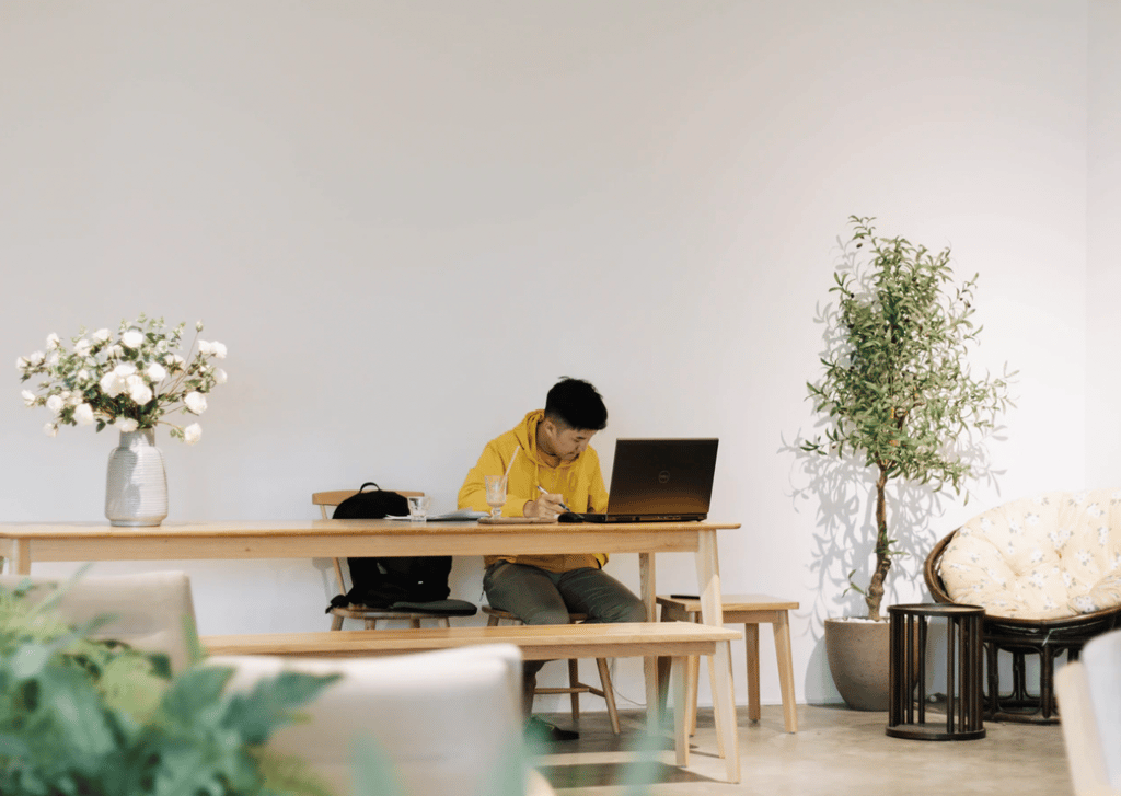 A photo by Nguyen Dang Hoang Nhu featuring a man working at a desk with flowers.