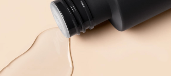 The Paula's Choice 2% BHA Liquid Exfoliant spilling on a pink background.