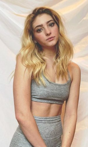 Willow Shields wearing a matching Beyond Yoga top and biker shorts in front of a white seamless background.