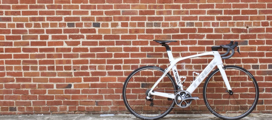  A white TREK Madone in front of a brick wall.