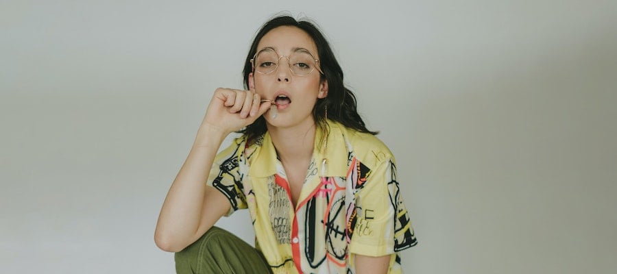 A Gen Z fashion influencer posing in round glasses and a yellow patterned shirt, by Elise Wilcox via Unsplash.