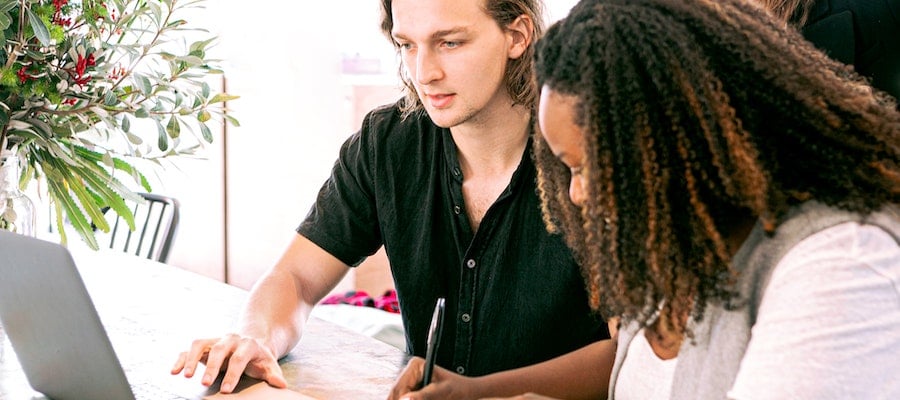 Two influencer marketing professionals working on a laptop, by Canva Studio.