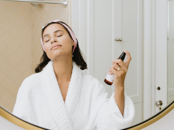 A skincare influencer applying a face mist, by Kalos Skincare via Unsplash.