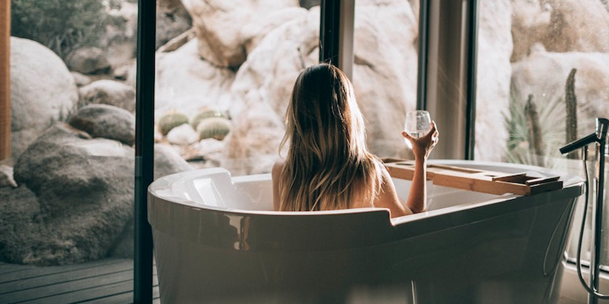 A woman in a bathtub holding a glass, by Roberto Nickson. 