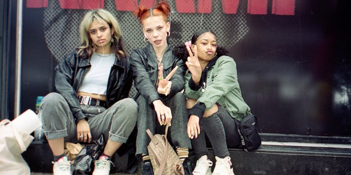 Three fashion influencers seated outside an event venue, by Matt Moloney.