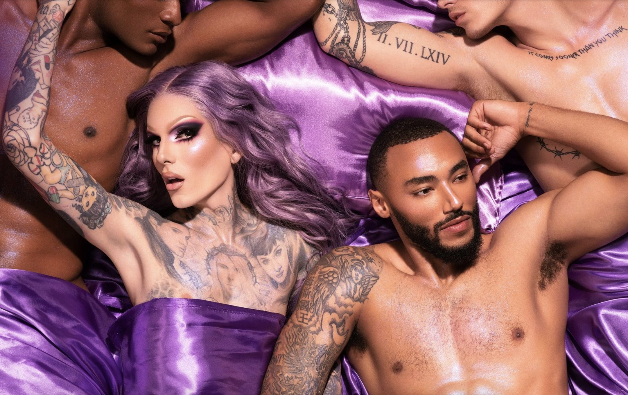 An advertisement for Jeffree Star Cosmetics’ Blood Lust Collection, featuring Jeffree Star himself laying with scantily clad men on a purple silk sheet.