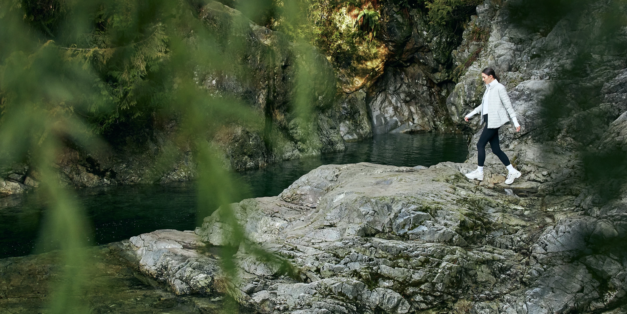 A woman hikes by a creek in a Lululemon ad.