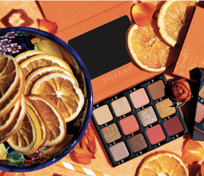 A photo featuring Viseart’s Spritz Edit Eyeshadow Palette laying among orange slices and orange roses. 