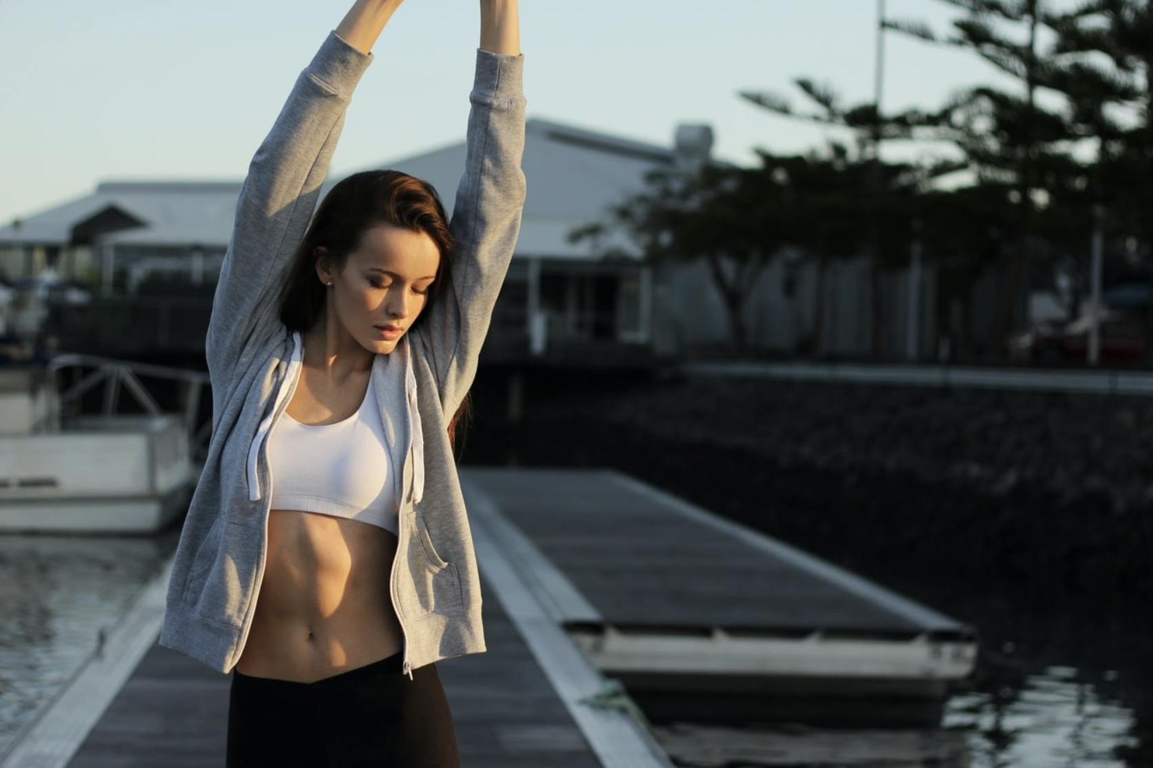 A fitness influencer in clothing from an athleisure brand stretching on a dock. 