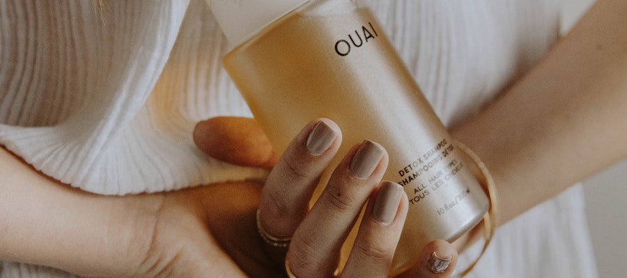 The hands of a woman holding a bottle of Ouai’s Detox Shampoo, by Mathilde Langevin.
