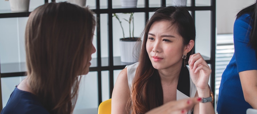 Two young women discussing influencer marketing strategy, by Mimi Thian. 