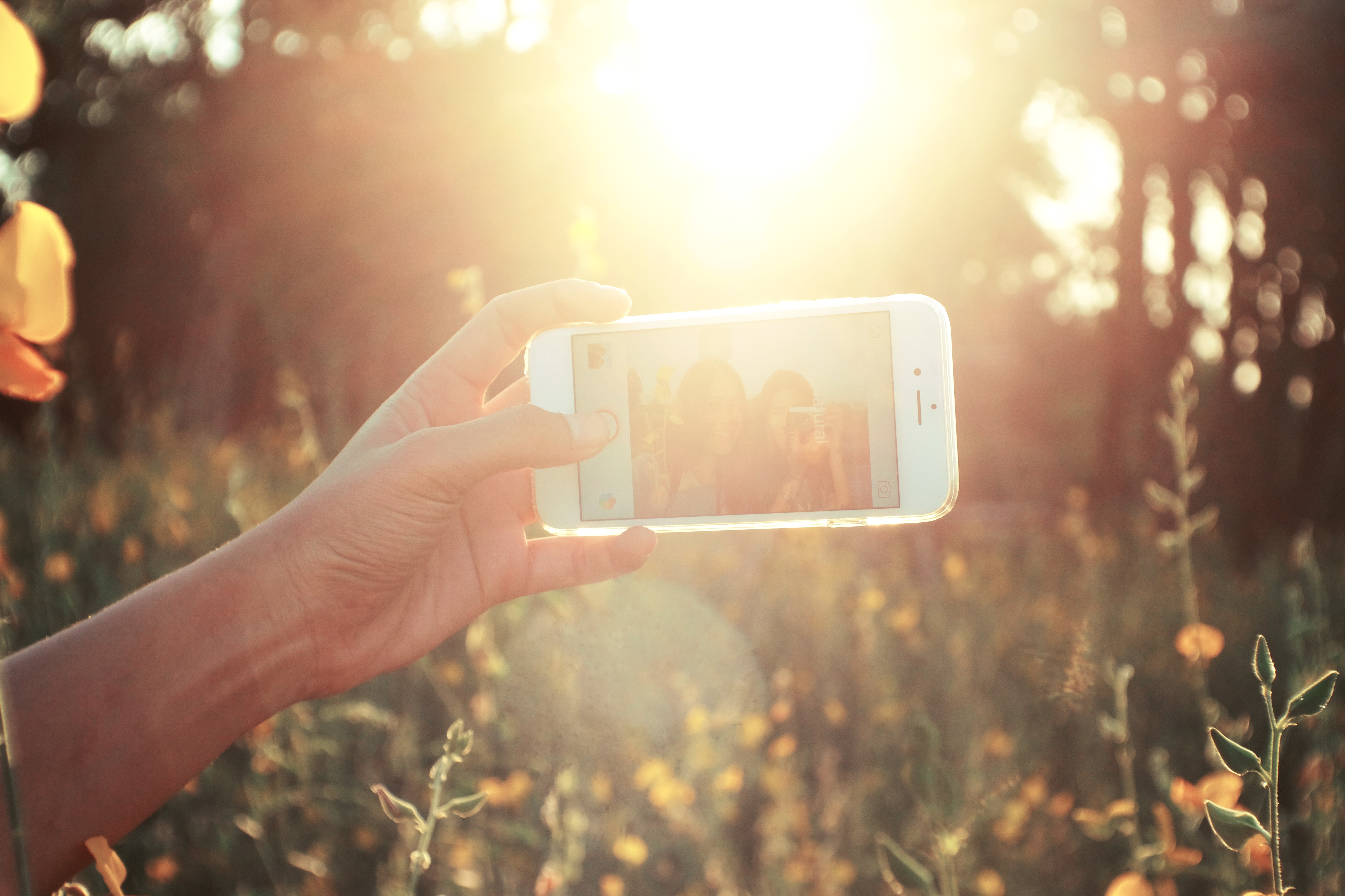 A person holding up a smart phone to take a selfie.